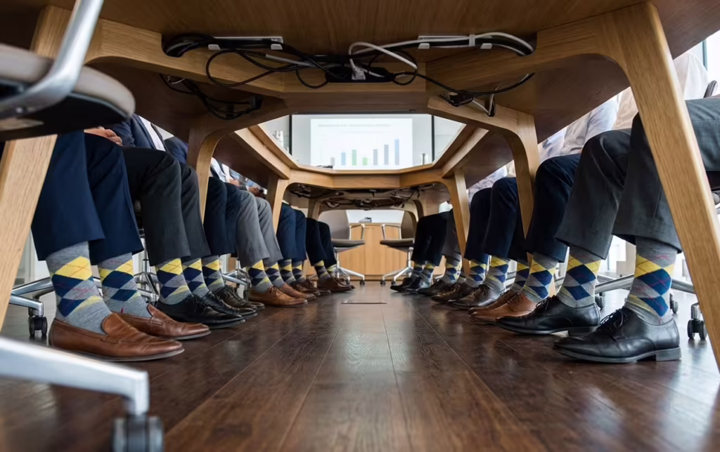 A group of business professionals standing together, wearing various argyle-patterned socks.